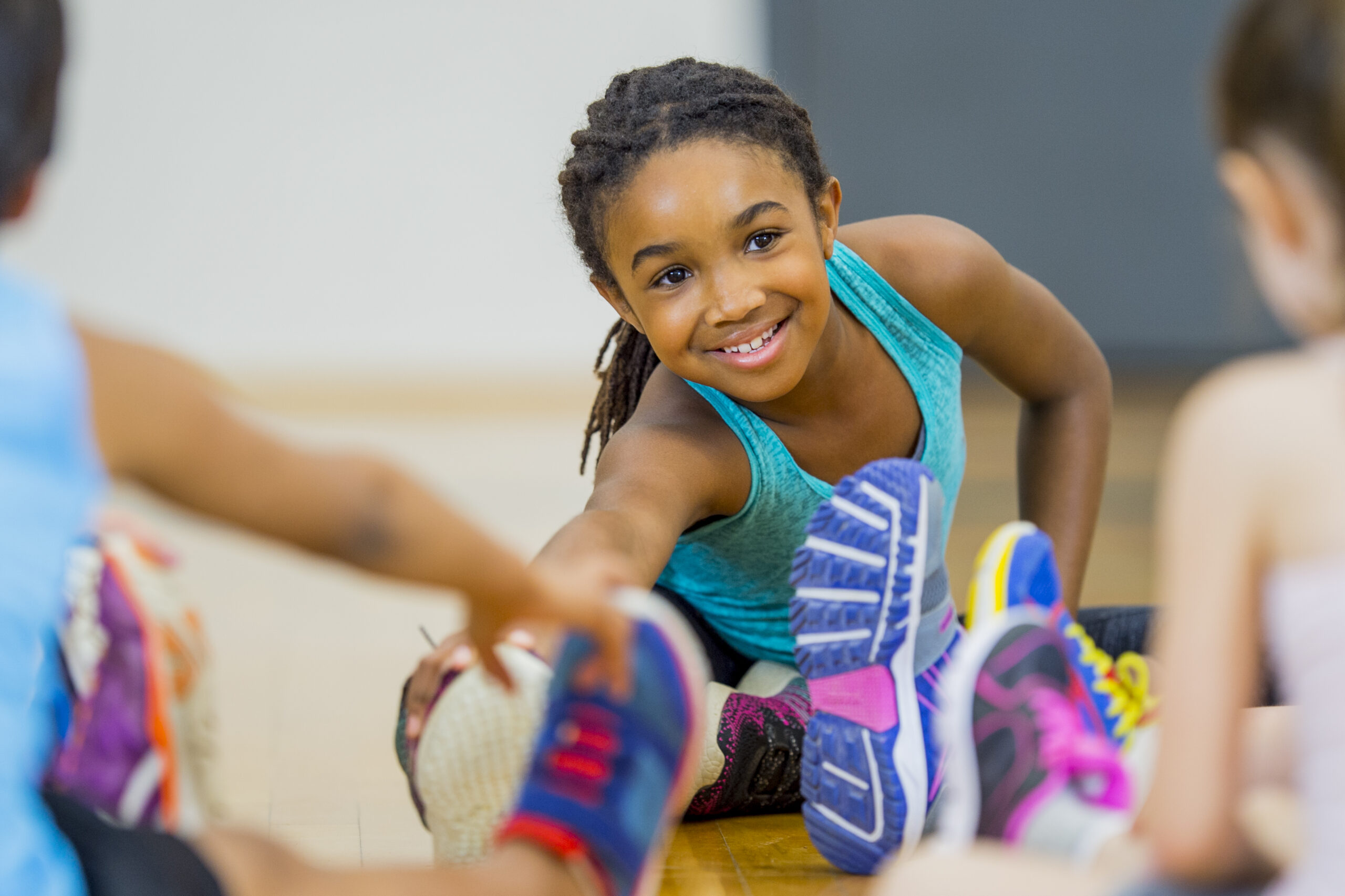 A young African American girl leads a stretch during gym class as part of their yoga routine.