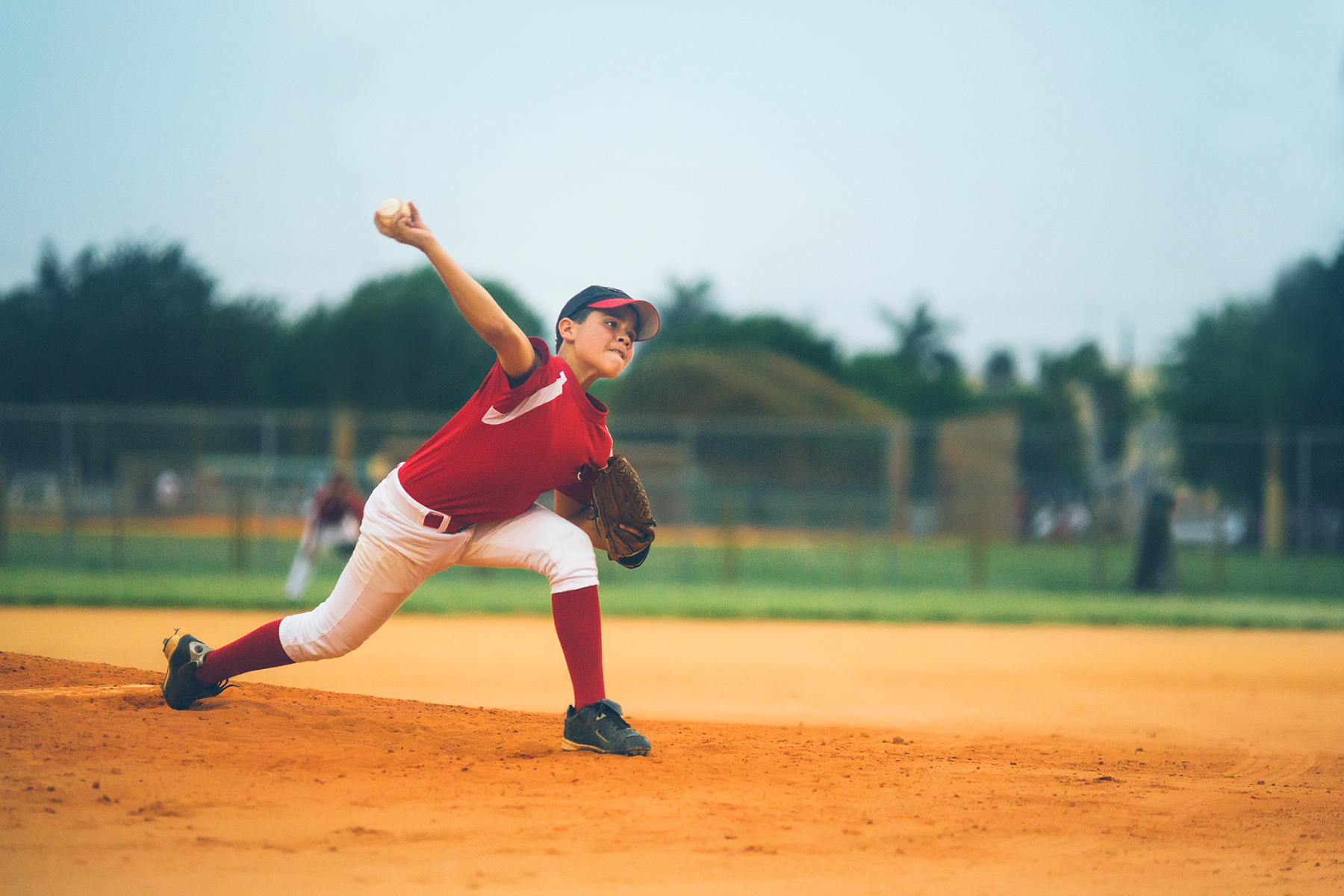 a kid pitching a baseball on a baseball field