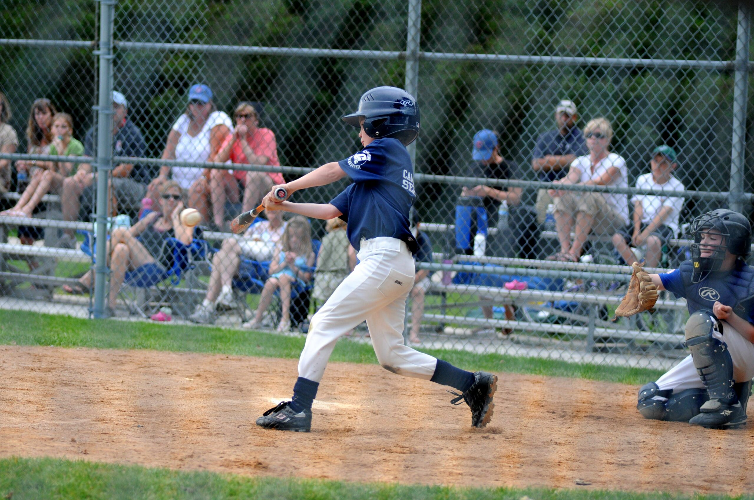 a kid swinging a bat to hit a baseball