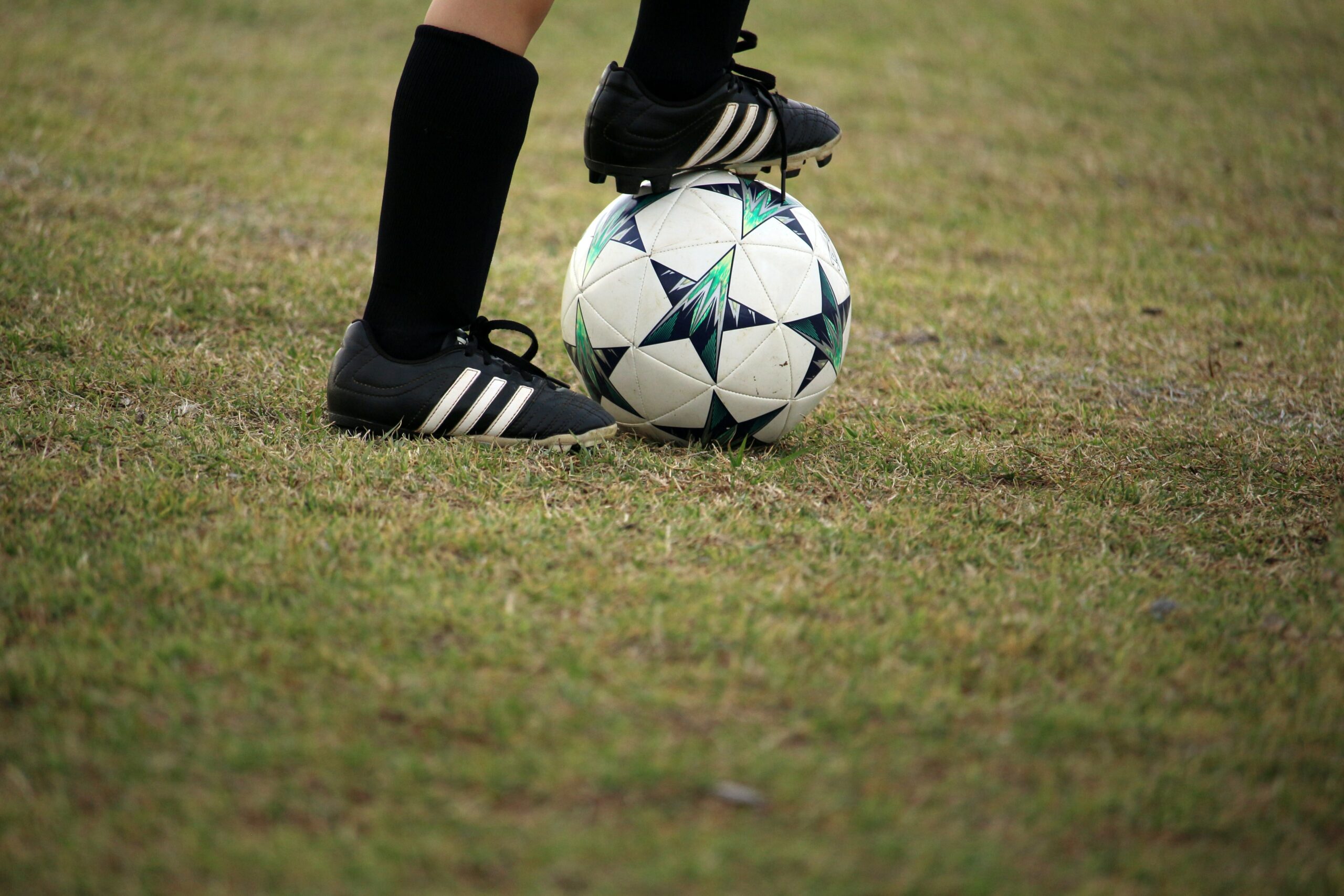 a child on a field with their cleat on a soccer ball
