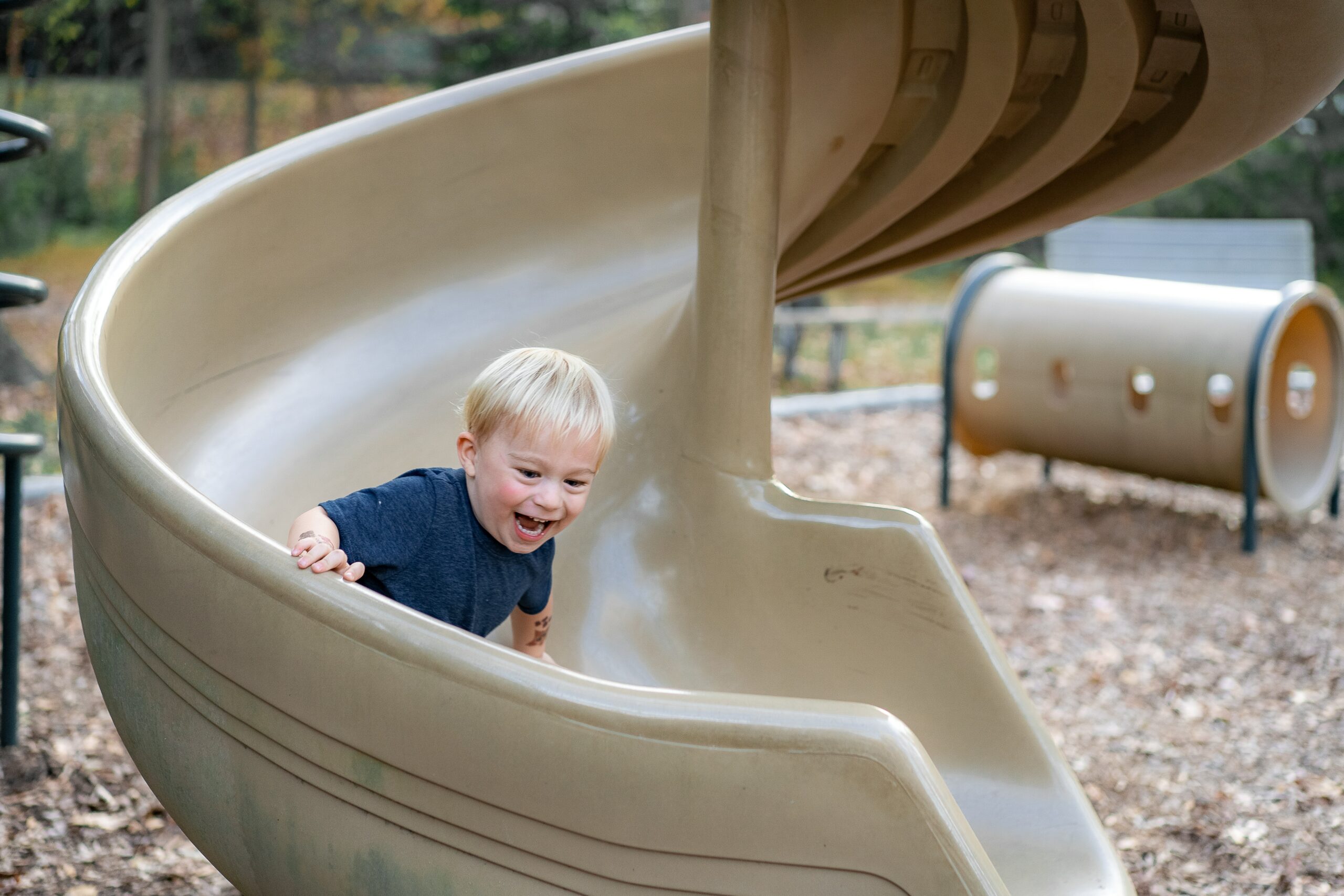 A child comes down a slide on a playground.
