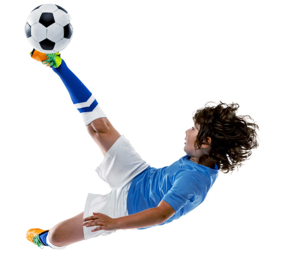 boy in soccer uniform jumping and kicking a ball in the air