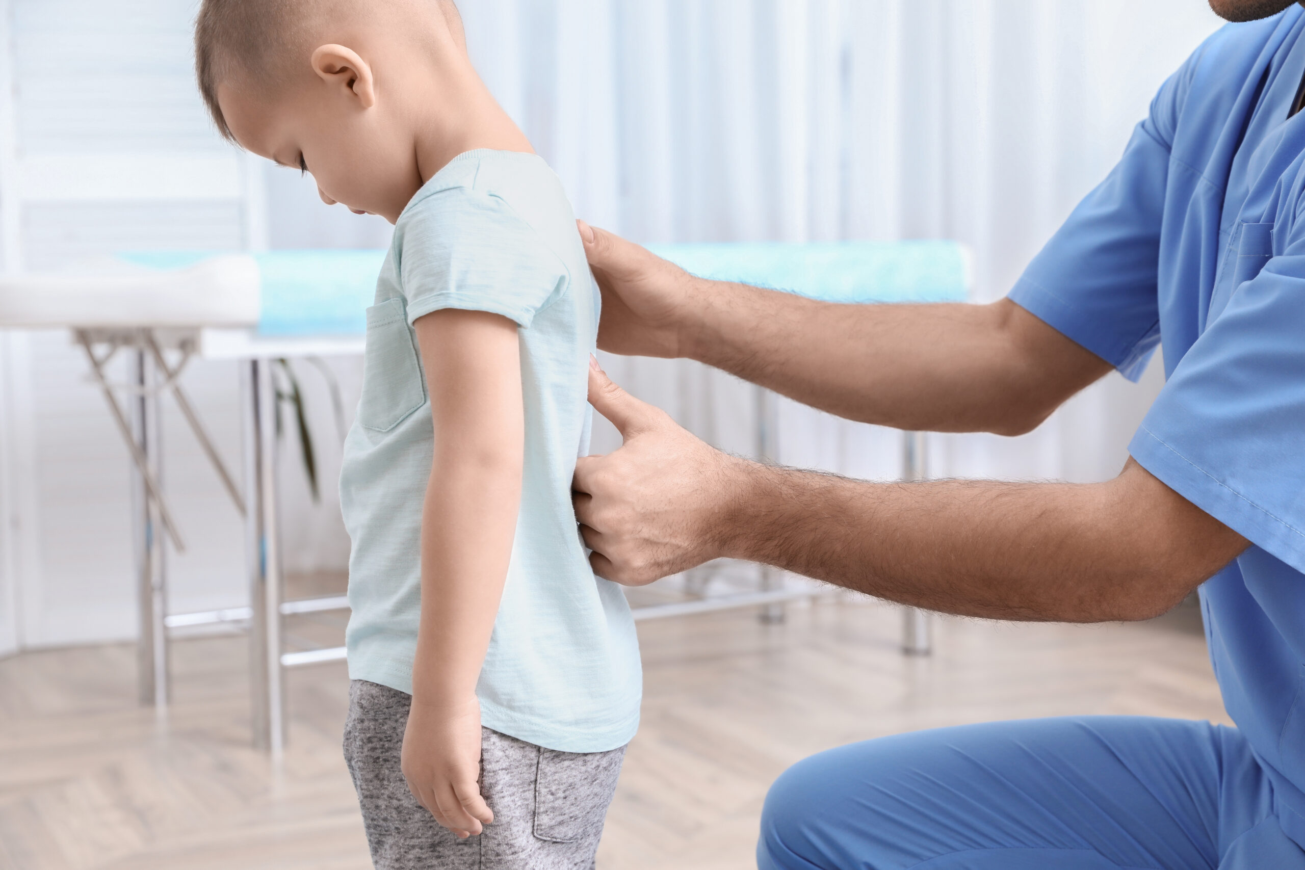 a doctor checking a child's spine in a doctor's office