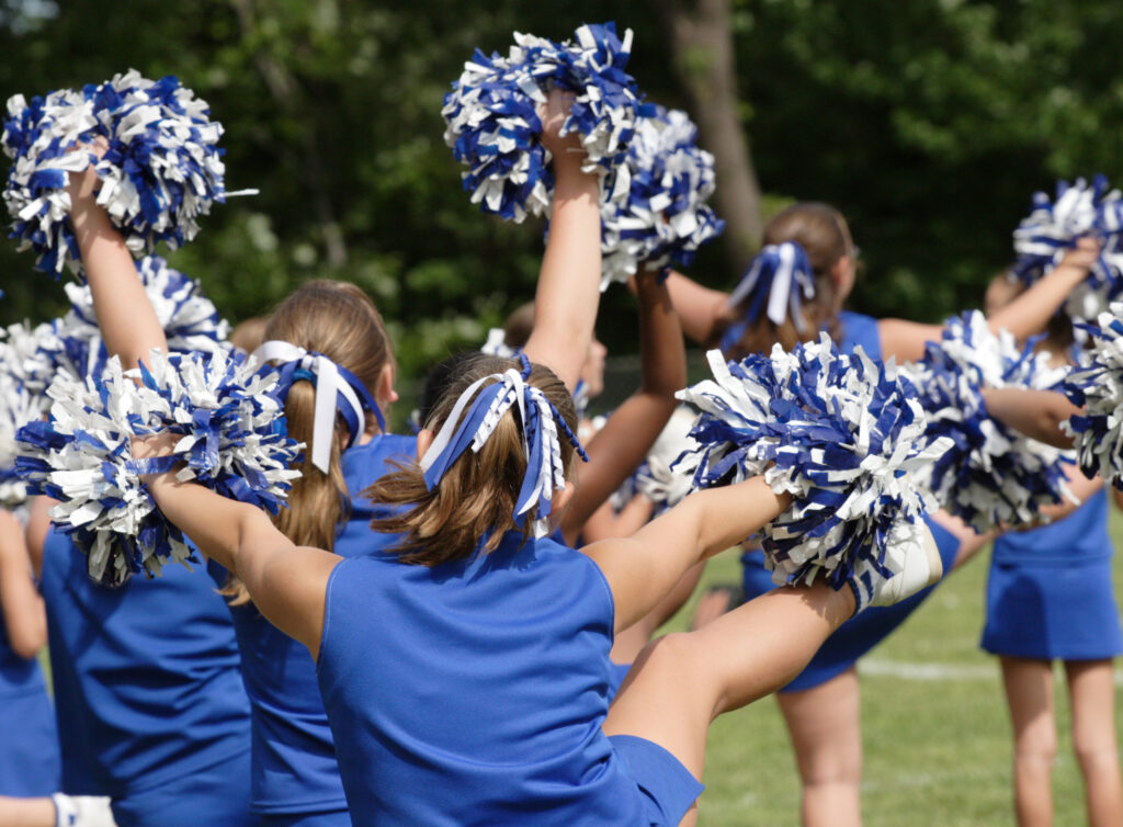 a group of cheerleaders practicing a routine with pom-poms