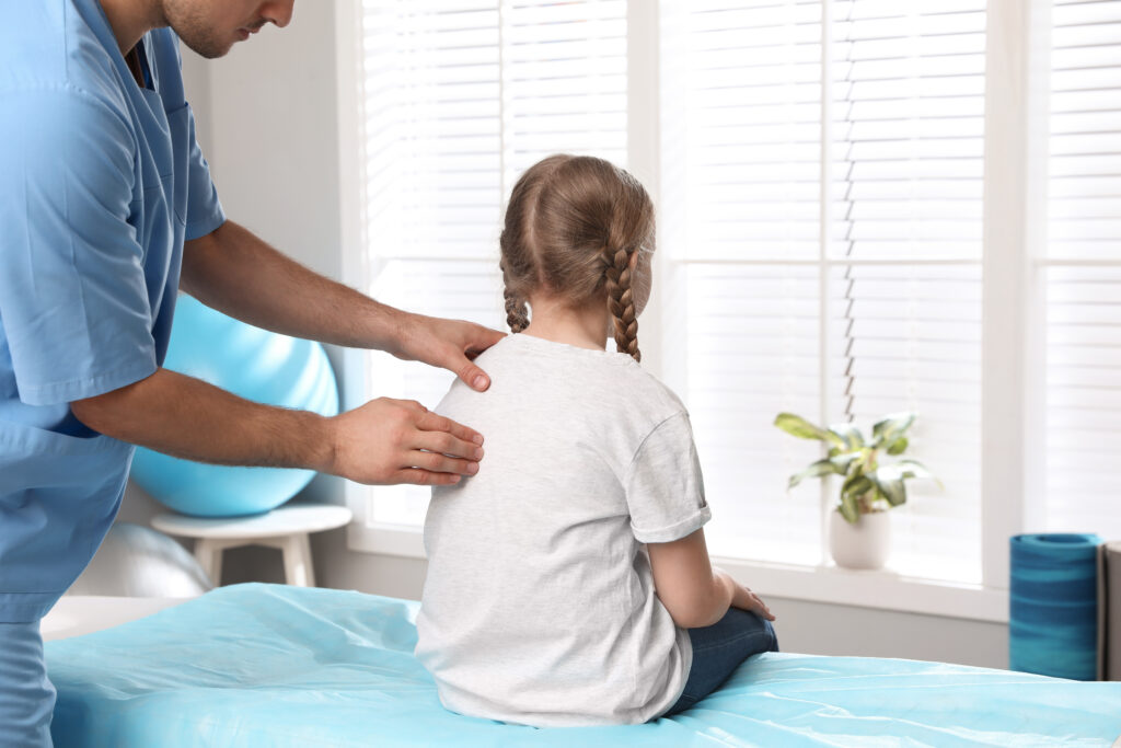 Orthopedist examining child's back in clinic, closeup. Scoliosis treatment